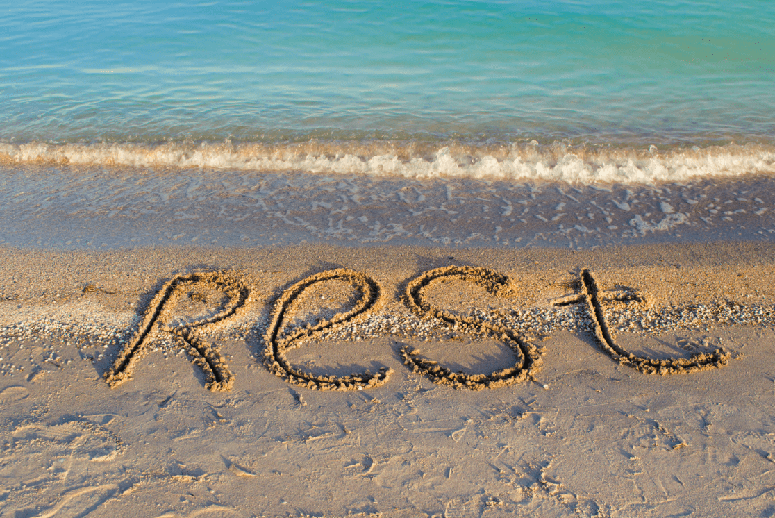 REST written in sand on the beach.