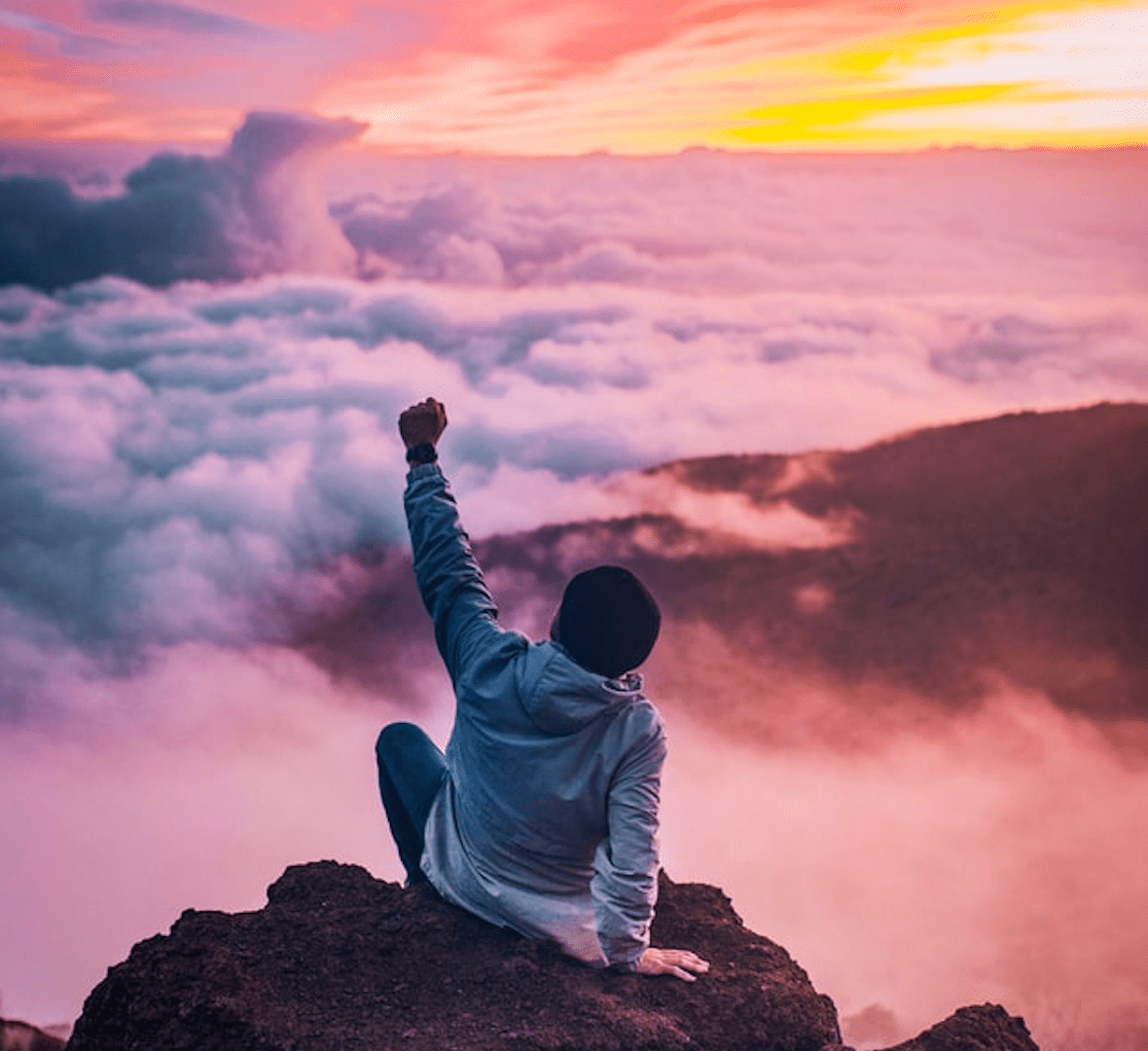 Happy guy with one arm raised at sunset.