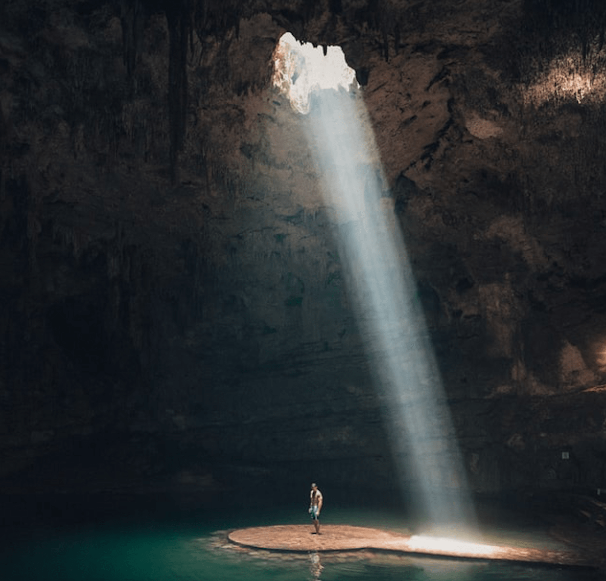 man standing in a cave with light cascading down on him.
