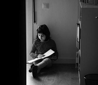 Black and white filter on an image of a little girl reaching a book on the kitchen floor.