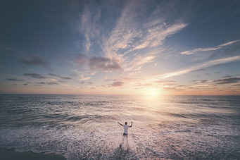 Sunset with man on the shore watching the tide.