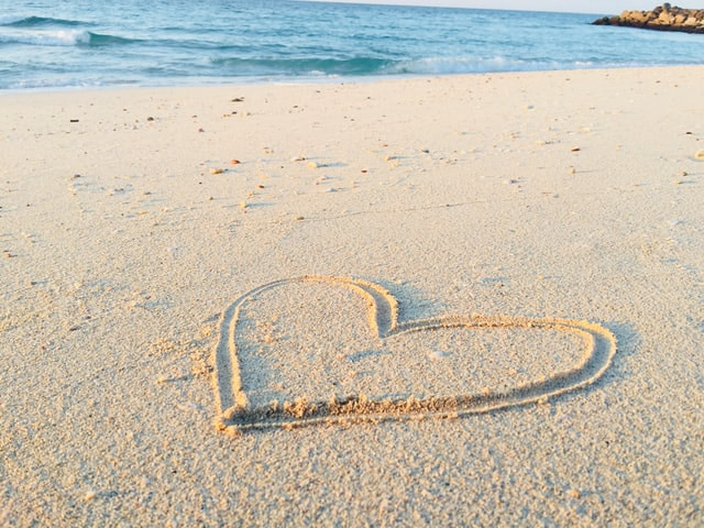 Heart traced in the sand by the beach.