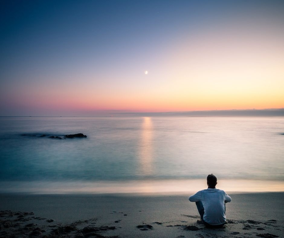 Man meditating on a beach.