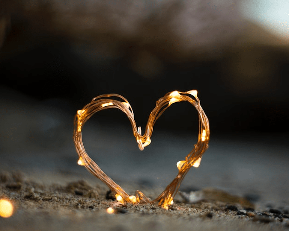 Heart with lights on it at a sandy beach